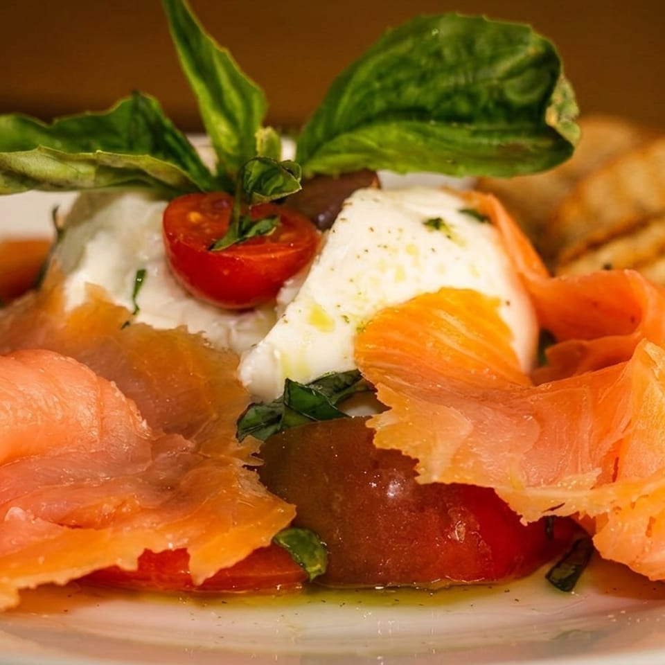 Smoked salmon, fresh mozzarella, cherry tomatoes, and basil drizzled with olive oil, served with toast.